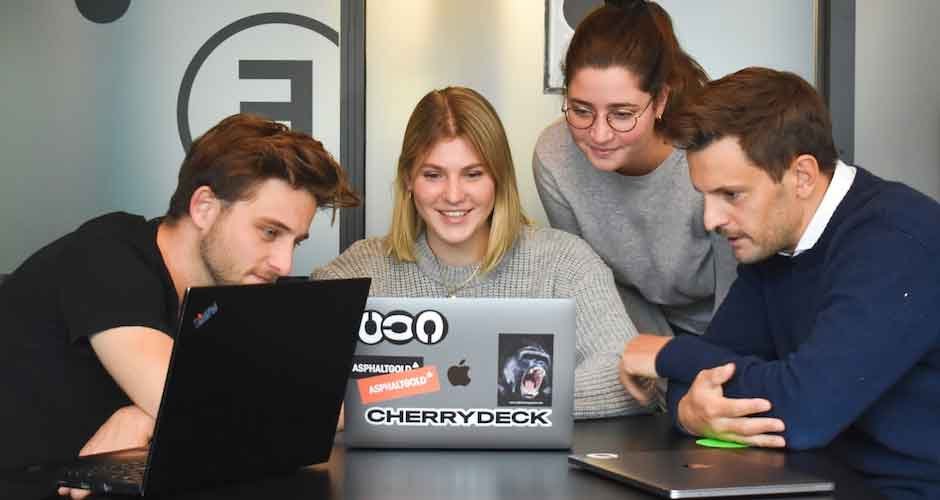 Four people looking at a laptop learning about what is resource utilization.